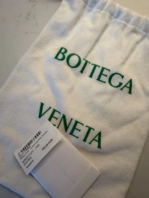 Svart flätad plånbok Bottega Veneta - Säljer nu min fina plånbok från Bottega Veneta i äkta läder med deras ikoniska flätade mönster. Plånboken har dragkedja runtom och gröna detaljer längs kanten. Väldigt bra skick! Säljer för: 3000kr köpt för: 8000kr 
