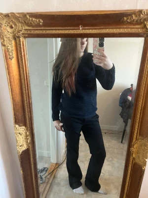 Mörkblå ribbstickad tröja - Säljer en mörkblå ribbstickad tröja med rund hals och långa ärmar. Tröjan har en enkel, stilren design och är gjord i ett mjukt stickat material som passar perfekt till jeans eller byxor. Perfekt basplagg för garderoben.