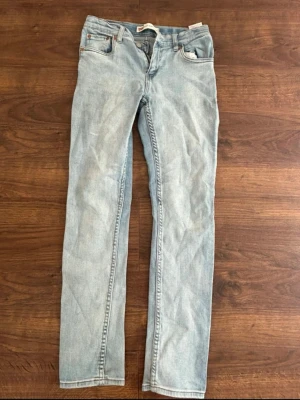 Ljusblå raka jeans från Levi's - Säljer ett par ljusblå jeans från Levi's med klassisk femficksdesign och raka ben. Jeansen har en snygg tvättad look och är tillverkade i bomull. Perfekta för en avslappnad stil.