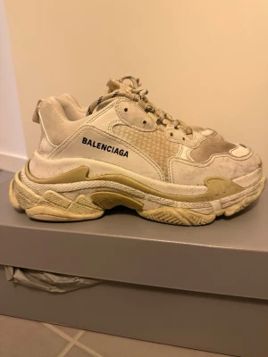 Balenciaga Triple S sneakers beige - Chunky sneakers från Balenciaga i modellen Triple S. Skorna är beige och vita med svarta detaljer och har en kraftig sula i flera lager. Materialmix av mesh, läder och gummi. Balenciaga-logga på sidan och storleksnummer framtill. Köpta utomlands, kvitto finns och kartong medföljer 