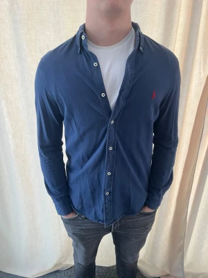 Blå skjorta från Ralph Lauren - Klassisk blå skjorta från Ralph Lauren. Riktigt snygg. Bra skick. Strl M, personen på bilden är 184 cm lång. Skicka gärna prisförslag 