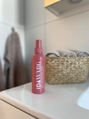 IDAWARG Heat Protection Spray - Värmeskyddsspray från IDAWARG i stilren design, matt rosa flaska med vit text. Perfekt för att skydda håret mot värme från stylingverktyg. Säljer till någon som är nöjd med hennes produkter och vill ha den för ett billigt pris. Eftersom halva flaskan är använd, så  innehåller det ungefär 75 ml. 