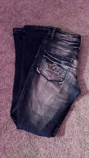 jeans med broderade fickor - Låg midjade jeans med kronor på fickorna och fin tvätt. 35 cm över midjan (stretchigt material) och 76 cm på innerbenet. 💞 Litet hål som syns på sista bilden 🕵️‍♂️