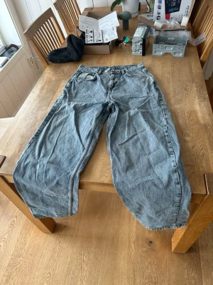 Baggy ljusblå jeans med bred passform - Säljer ett par baggy ljusblå jeans med bred passform reclaimed vintage märke och klassiska fem fickor. Jeansen har en avslappnad look och är tillverkade i denim. Perfekt för dig som gillar streetstyle och vill ha ett par riktigt bekväma jeans.