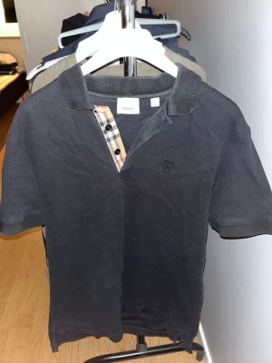 Svart Burberry t-shirt med rutiga detaljer - Svart t-shirt från Burberry med klassisk krage och korta ärmar.