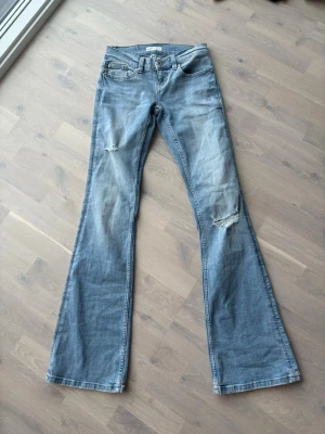 Bootcut jeans från Perfect Jeans - Snygga ljusblå bootcut jeans från Perfect Jeans med slitningar på låren och knäna. Klassisk femficksmodell och låg midja. Perfekta för dig som gillar en avslappnad och trendig stil. Storlek xs tall