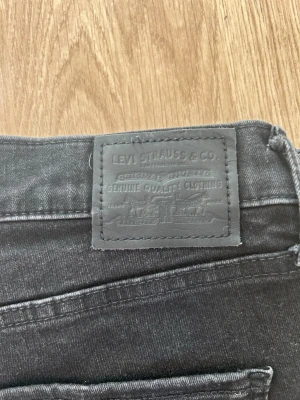 Svarta jeans från Levi's - Snygga svarta jeans från Levi's med klassisk femficksmodell och diskret logotyp på bakfickan. Jeansen har en mörk tvätt och är tillverkade i slitstark denim. Perfekta för dig som gillar en stilren och tidlös look.