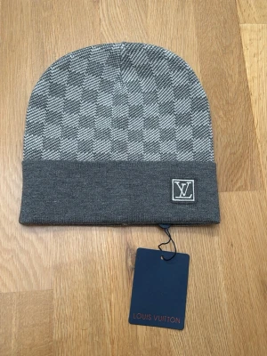 Grå  mössa med rutmönster - Snygg grå mössa  med klassiskt rutmönster och vikt kant. Mössan är helt ny och de är bara att komma med prisförslag. 