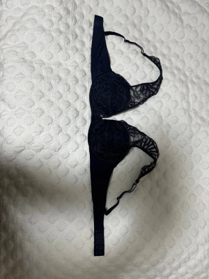 Mörkblå behå - Denna behå har spetsdetaljer på kuporna och axelbanden. Den har justerbara axelband och en hak- och hyskknäppning i ryggen. Använd och testad en gång.