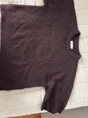 Brun stickad tröja från NA-KD - Mysig brun stickad tröja från NA-KD med rund halsringning och ribbade detaljer vid hals och nederkant. Tröjan har korta ärmar