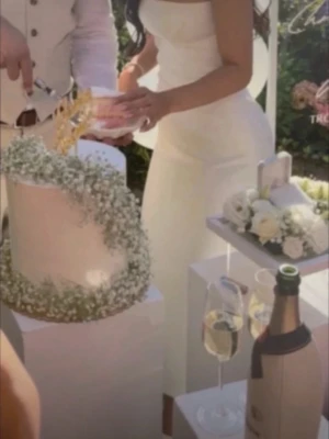 Vit axelbandslös långklänning - Stilren vit axelbandslös långklänningco med figurnära passform och raka linjer. Klänningen har två dekorativa ficklock framtill och en moldad överdel som ger en elegant siluett. Perfekt för dig som vill ha en minimalistisk och modern look.