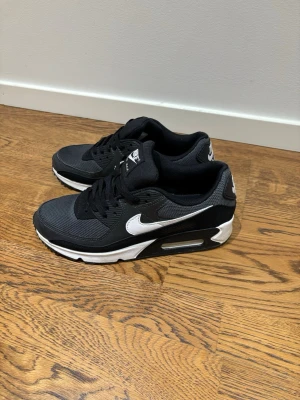 Nike Air Max 90, storlek 41 - Jag säljer ett par svarta air Max 90 i storlek 41, skorna är nästan helt nya och bara köpta för 1 månad sedan så det är inga fel på dem. Jag kommer även tvätta skorna med ett shoe cleaner kit innan jag skickar dom så att dom blir helt fräscha. Skorna köptes för 1700 men säljs nu för 750