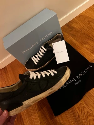 Svarta Philippe Model skor - Snygga svarta sneakers från Philippe Model , sko snörena har jag bytt men man får med orginal snörerna också. Sulorna har knappt inga tecken på andvändning men skriv till mig om ni vill ha bild på dom också , Box och dust bag ingår , pris kan diskuteras vid snabb affär!😊