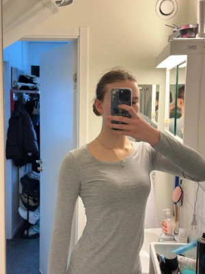 Grå långärmad topp från ginatricot - En enkel och stilren grå långärmad topp från Divided. Toppen har rund halsringning och är gjord i mjuk bomull som känns skön mot huden. Passformen är normal och den är perfekt att matcha med jeans eller kjol för en clean look.