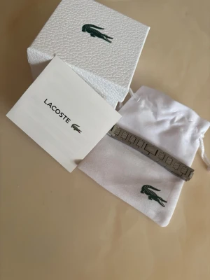 Silverfärgat armband från Lacoste - Snyggt oanvänd armband från Lacoste. Den är 20cm lång men kan enkelt justetas kan hjälp med det om det behövs😊