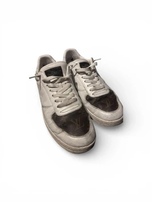 Louis Vuitton skor - Säljer ett par snygga LV (Louis Vuitton) sneakers i storlek 42. Vit design med klassiska monogramdetaljer i brun färg som ger en exklusiv och stilren look. Passar perfekt till både vardag och streetwear outfits.  Skorna är använda och har normalt slitage (se bilder), men är fortfarande i bra skick och fullt användbara. Bekväma och sitter bra på foten.  Storlek: 42 Skick: Använt, bra skick Färg: Vit/Brun. Skickas snabbt och packas noggrant 💬 Hör av dig vid frågor/fler bilder.
