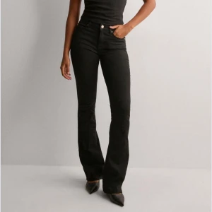 Svarta bootcut jeans med hög midja - Snygga svarta bootcut jeans med hög midja och klassiska fem fickor. Jeansen har en smickrande passform och är tillverkade i stretchigt denimtyg för extra komfort. Perfekta till sneakers eller klackar för en trendig look.