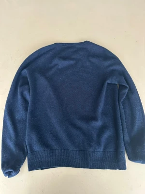 Mörkblå stickad tröja Morris - Mysig mörkblå stickad tröja från Morris med rund halsringning och diskret logga broderad på bröstet. Tröjan har ribbade muddar vid ärmslut och nederkant. Perfekt för lager på lager och enkel att matcha.