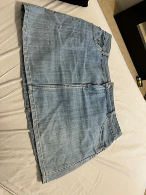 Ljusblå jeanskjol i klassisk modell - Snygg ljusblå jeanskjol med klassisk femficksdesign och dragkedja framtill. Kjolen har en rak passform och är perfekt för en avslappnad stil. Passar till både sneakers och boots.