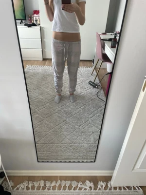 Rutiga pyjamasbyxor i pastellfärger - Mysiga pyjamasbyxor med rutigt mönster i ljusa pastellfärger som rosa, grått och vitt. Byxorna har resår i midjan och är raka i modellen med smala benslut. Perfekta för chillkvällar hemma.