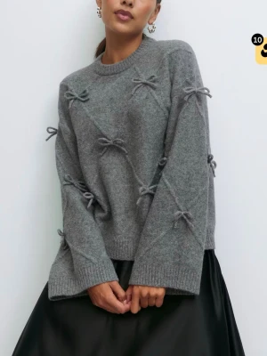 Grå stickad tröja med rosetter - Supersöt grå stickad tröja med dekorativa rosetter över hela tröjan. Tröjan har rund halsringning, långa ärmar och ribbade muddar. Perfekt för dig som vill ha en mysig men ändå unik look. Använd endast 1 gång❤️