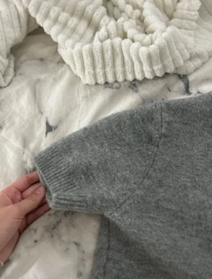 Grå stickad tröja från Zara - Mysig grå stickad tröja från Zara med rund halsringning och ribbade muddar vid ärmslut och nederkant. Tröjan har en enkel och stilren design, perfekt för lager på lager och passar till det mesta. Knappt använd