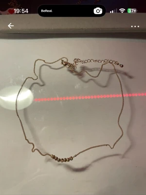 Guldfärgat halsband med pärldetaljer - Snyggt och stilrent halsband i guldfärgad metall med små pärlor på rad framtill. Kedjan är tunn och har ett justerbart lås för perfekt passform. Perfekt accessoar för att lyfta din outfit. Min 38cm max 46cm💛aldrig använt