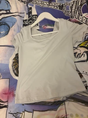 Ljusvit croppad topp med kort ärm - En enkel och stilren ljusvit topp med croppad passform och korta ärmar. Toppen har en rundad halsringning med en extra banddetalj över bröstet. Perfekt att matcha med jeans eller kjol.