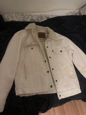 Beige jeansjacka med teddyfoder Levi's - Säljer en snygg vit jeansjacka från Levi's med mysigt teddyfoder och klassisk krage. Otroligt varm. Passar M också. Perfekt nu till våren