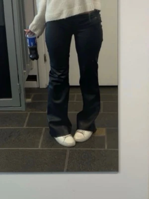 Svarta utsvängda byxor från Nelly - Säljer jättefina skinnbyxor ifrån Nelly. Dom är sydda lågmidjat och är lite skadade längst ner på byxan!