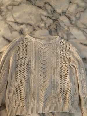 Vit kabelstickad tröja från Zara Knit - Säljer en vit kabelstickad tröja från Zara Knit med snygga flätmönster och hålstickade detaljer. Tröjan har rund halsringning, långa ärmar och ribbade muddar. Är liten i storleken så passar barn kläder i st 146/152 ❤️💐🥹