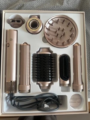 Multifunktionell hårstyler 7-i-1 - Säljer en multifunktionell hårstyler med sju olika tillbehör för styling, torkning och volym. Inkluderar rundborste, plattborste, locktillbehör och diffuser. Perfekt för att skapa olika frisyrer hemma. Den är köpt från Kjell & Company.