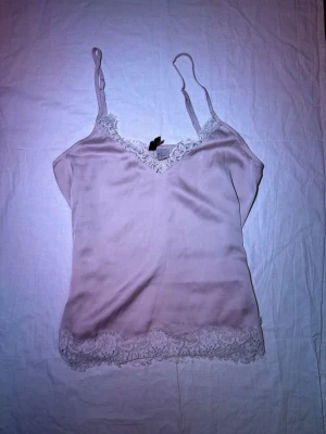 Rosa silkestopp - Gulligt rosa silkeslinne med spetskant                                       Justerbara band.                                                     Använd fåtal gånger.                                              Står 32 men skulle säga XS.                                Gammelrosa färg