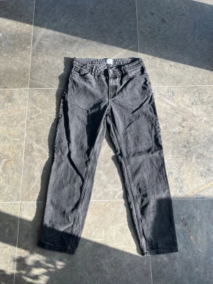Svarta jeans - Säljer ett par svarta jeans från KidsBrandStore. Jeansen har klassiska fem fickor, bälteshällor och knappgylf. Materialet är kraftig denim i bomull. Perfekta för en avslappnad och trendig look. Fint skick på dem, hör av er om ni har frågor.