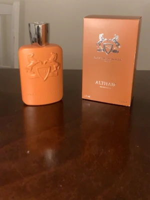 Parfums de Marly Althair EdP 125ml - Exklusiv parfym från Parfums de Marly, modellen Althair. Flaskan är matt orange med silverfärgat lock och har ett elegant reliefmönster med två hästar och sköld. Kommer i matchande orange kartong med silverdetaljer. En lyxig doft för dig som vill sticka ut.