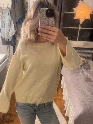 Ljusgul oversized stickad tröja - Mysig ljusgul stickad tröja med avslappnad, oversized passform och breda ärmar. Tröjan har ribbade muddar vid ärmslut och nederkant samt rund halsringning. Perfekt för lager på lager och en chill look. Pris kan diskuteras🤗