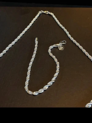 Flätat silverfärgat halsband -  Halsband& matchande armlänk i elegant rope design . Halsbandet är ca 60 cm och väger ca 19 gram, armlänken är 29 cm och väger 9 gram. Båda har 925 stämpel .Båda har 925 stämpel och är pläterade 92.5%