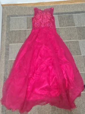 Lång röd klänning med spets och paljetter - Det var från dubai och har använt den 1 gång. Snygg långklänning i stark röd färg med detaljerad spets och paljetter på överdelen. Klänningen är ärmlös och har en transparent mesh upptill som ger en elegant look. Perfekt för dig som vill sticka ut på bal eller fest.