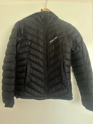Dunjacka Peak Performance  - Säljer en Peak Performance W Frost Down Hood jacka. En stilren och bekväm dunjacka som är både lätt och varm. Perfekt som en lite varmare jacka under kyliga dagar.