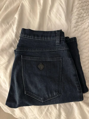 Mörkbblå bootcut jeans Abrand - Säljer ett par blå bootcut jeans från Abrand med klassisk femficksdesign och en liten logotyp på bakfickan. Säljer då jeansen är för små, endast använda 4 gånger. Väldigt bra skick. Nypris 900. Andra bilden är modellen i annan färg. 