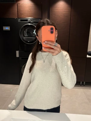 Beige stickad tröja med rund hals , VERO MODA - En enkel och stilren beige stickad tröja med rund hals och långa ärmar. Tröjan har ribbstickade muddar vid ärmslut och nederkant. Perfekt för lager-på-lager och passar till jeans eller kjol. Materialet ser ut att vara mjukt och bekvämt.