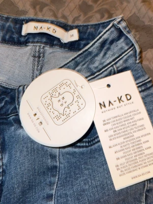 Blå raka jeans från NA-KD - Säljer ett par blå raka jeans från NA-KD med hög midja och klassisk femficksdesign. Jeansen har en tvättad look och raka ben med sömdetaljer framtill. Perfekta för en avslappnad och trendig stil.
