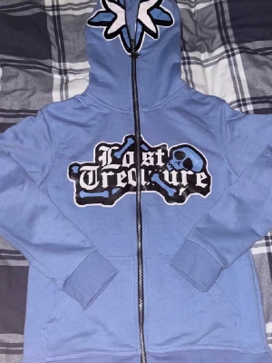Blå hoodie - Snygg tröja, skön att ha på sig och har snyggt tryck. Står ”lost treasure” på framsidan. 