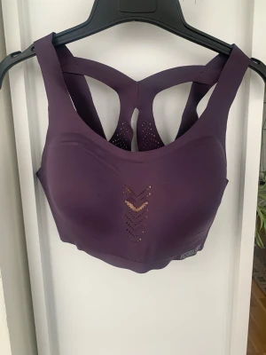 Lila sport-bh från Victoria Sport - Supersnygg lila sport-bh från Victoria Sport med breda axelband och coolt ryggparti i mesh. Bh:n har ventilerande hålmönster framtill och bak, samt en stabil och bekväm passform. Perfekt för träning och aktiva dagar, storlek 38D/ 85D. Använd vid enstaka tillfällen och är i väldigt bra skick 