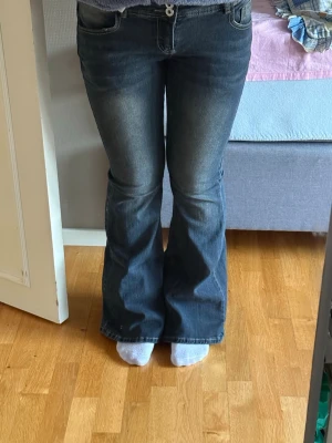 Blå bootcut jeans  - Säljer ett par blå bootcut jeans med lätt slitna detaljer framtill. Jeansen har klassisk femficksmodell, normal midja och dragkedja med knapp. Materialet är denim i bomull med mycket stretch för skön passform. Perfekta för dig som gillar retrovibbar och avslappnad stil. Aldrig använt, bara testat. 