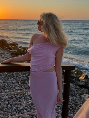 Asos - Ljusrosa set - Säljer ett ljusrosa set med oneshoulder-design i toppen och en långkjol. Materialet är stretchigt och luftigt och väldigt skönt på sommaren. Storlek S i kjolen och storlek M i toppen.