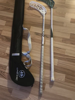 Innebandyset med klubbor och glasögon - Säljer ett innebandyset med två vita innebandyklubbor från Oxdog och Unihoc, samt ett par blå-genomskinliga skyddsglasögon från Oxdog i originaletui. Perfekt för träning eller match. Medföljer även en svart Unihoc-väska för enkel transport.