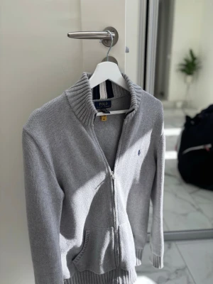 Polo Ralph Lauren grå hel zip  - Snygg grå ziptröja från Polo Ralph Lauren. Använd ett fåtal gånger, skick 10/10. Köpt på Zalando för 1595. Storlek 18-20 xl (xs)Hör av er vid minsta fundering och fråga🤝💯🙏