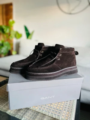 Bruna mockakängor från Gant - Snygga bruna kängor i mocka från Gant med grov sula och klassisk snörning. Skorna har stilrena sömmar och metallöglor för snörena. Perfekta för dig som gillar en stilren och modern look. Storlek 42, kan passa de som har 43 med.  Ordinariepris: 2000kr