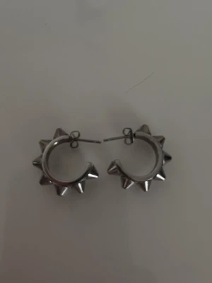 Peak Creoles S Steel örhängen - Snygga örhängen i creolmodell från Edblad, tillverkade i blankt rostfritt stål. De har en cool design med spetsiga nitar runt hela ringen som ger en edgy vibe. Dessa är i nyskick.